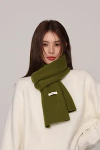 Detail showing the 100% Australian wool wash label on olive green knitted scarf