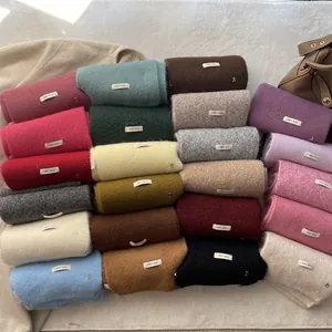 Stack of colorful knitted wool scarves in various solid shades for winter season
