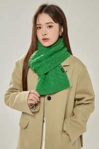 Close-up of emerald green cable knit wool scarf with 100% wool label on cashmere coat