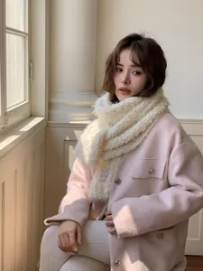 Detailed close-up of soft cream white sherpa wool scarf with brand label on pink coat