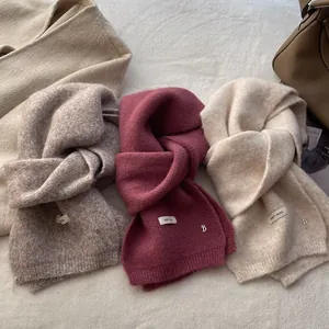 Three knit scarves in beige, burgundy, and ivory with soft texture and metallic B detail