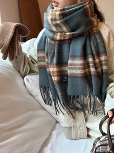 Close-up of navy and brown checkered scarf with long tassels and soft knit gloves