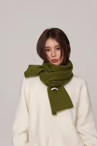 Close-up of deep green 100% wool scarf texture paired with a white knitted sweater