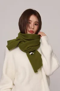 Close-up of olive green knitted wool scarf showing soft texture and 100% wool label