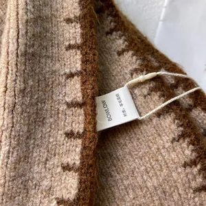 Dettaglio della sciarpa in misto lana con trama a maglia ed etichetta logo