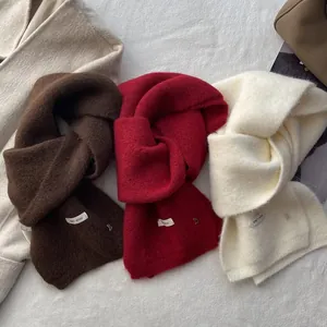 Chic knitted wool scarves in coffee, burgundy, and off-white on a plush background