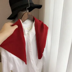 Détail de la texture en maille sur une écharpe triangle en laine rouge avec étiquette
