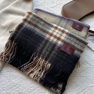 Detailed view of retro plaid tassel scarf with brand label on soft white fabric
