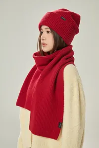 Detailtextur von rotem Strickschal und Mütze aus 100% Wolle an einem Modell
