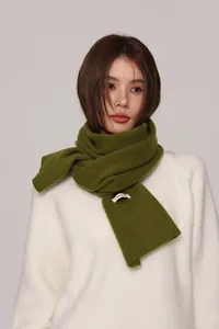 Detail of 100% pure wool scarf in matcha green showing soft knit texture and logo label