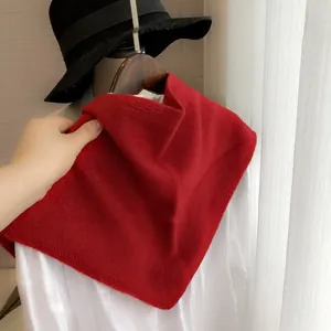 Détail du châle triangulaire en tricot rouge drapé sur une chemise blanche sur un mannequin