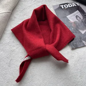 Détail d'une écharpe en maille rouge avec texture en laine douce et étiquette de marque