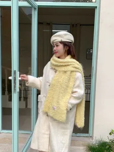 Detail of cream white coat with toggle buttons and a vibrant yellow plush winter scarf