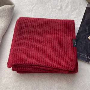 Detailansicht eines roten Schals aus 100% Wolle mit Rippenstrick und Materialetikett