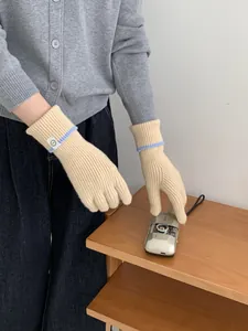 Gants en maille beige avec rayures bleues et écusson sourire montrant les détails tissés
