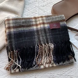 Detail of classic plaid scarf with blue and brown patterns and woven tassel fringe
