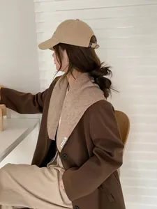 Gros plan d'un châle en tricot avoine avec étiquette blanche tissée sur un manteau en laine