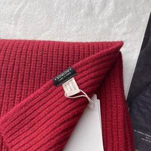 Nahaufnahme des Strickschals aus 100% Wolle in Dunkelrot mit Rippenmuster und Markenetikett