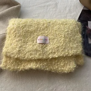 Detail shot of the creamy yellow plush texture and BOWLOW label on the winter handbag