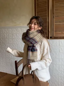 Close-up of winter plaid scarf with fringe detail in camel and wine red tones