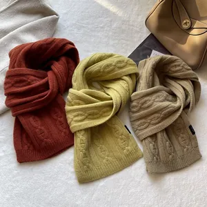 Close-up of thick cable knit wool scarves in brick red, ginger, and light coffee colors