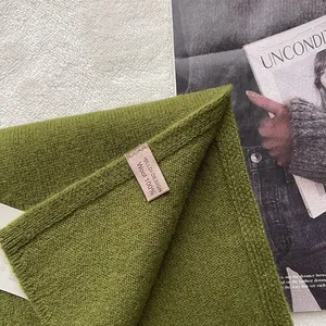 Close-up of olive green 100% Australian wool scarf featuring fine knit texture and brand label