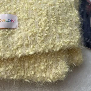 Macro view of creamy yellow bouclé wool scarf showing fluffy texture and OWLOW brand label