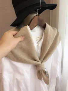 Vue détaillée de la texture du châle en tricot beige avec étiquette sur chemise