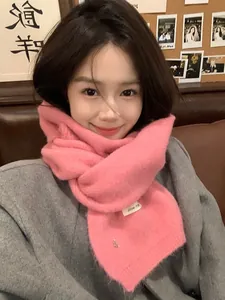 Close-up of a soft pink knitted wool scarf with delicate texture and a woven label