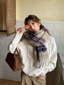 Detailed texture of burgundy and beige plaid scarf styled with white knit sweater