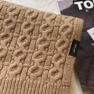 Detail of 100% Australian wool scarf featuring classic thick cable knit texture in camel brown