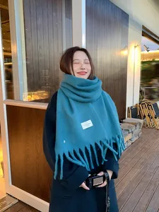 Detailed texture of peacock blue winter scarf with fringe and minimalist embroidery
