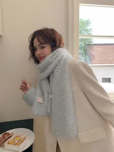 Close-up of a soft light blue fuzzy scarf featuring a pink brand label on plush fabric