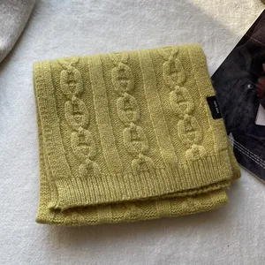 Detail of mustard yellow 100% wool scarf featuring chunky chain knit and ribbed hem edges