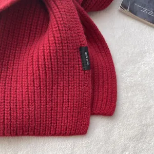 Detailaufnahme des roten Strickschals aus 100% Wolle mit Rippenstruktur und Stoffetikett