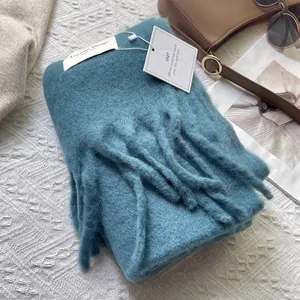 Detail of blue wool-like scarf with long tassels and premium brand label on knit surface