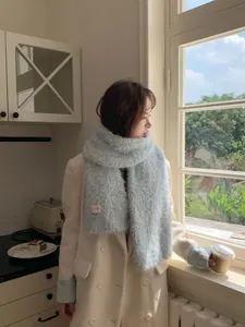 Detail of light blue fluffy mohair scarf texture styled with a beige winter coat