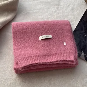 Detail of wool knit scarf in magenta pink with a luxury logo patch and metal B accent