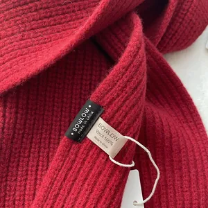 Detailansicht des roten Strickschals aus 100% Wolle mit Textur und Pflegeetikett