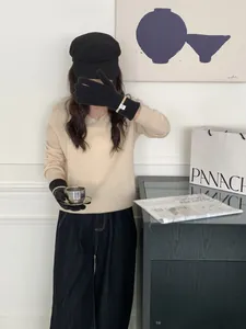 Gros plan de gants en tricot noir avec poignets côtelés beige et patch minimaliste