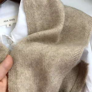 Détail de la texture d'un châle triangulaire en maille de laine de couleur beige