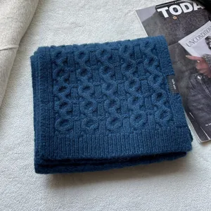 Detail of 100% wool knitted scarf with blue cable texture and authentic label