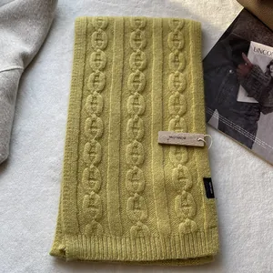Detailed knit texture of mustard yellow 100% wool scarf with authentic brand tag