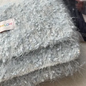 Close-up of soft light blue plush knit scarf with lowlow brand label and fuzzy texture