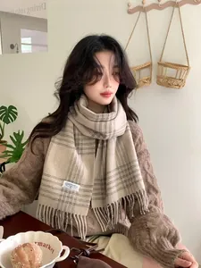 Detailed view of beige plaid wool scarf with fringes and minimalist woven brand label