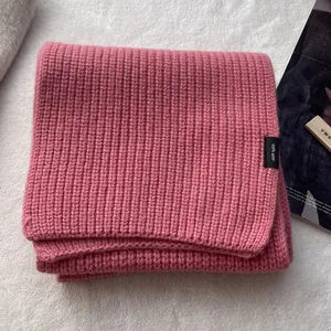 Detailaufnahme von rosa Wollschal aus 100% Wolle mit Rippstrick-Textur und Etikett