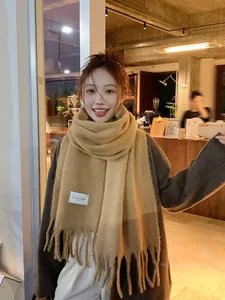 Detail of khaki wool-like scarf with long tassels and fabric label in a cafe setting