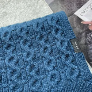 Detail of 100% wool knitted scarf with cable stitch texture and wash label in navy blue