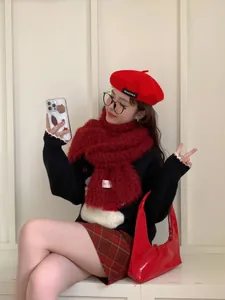 Detail shot of a plush dark red scarf styled with a beret and patterned sweater
