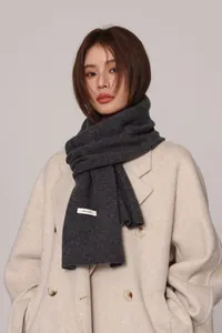 Detailed view of dark grey 100% pure wool scarf with woven label on winter coat